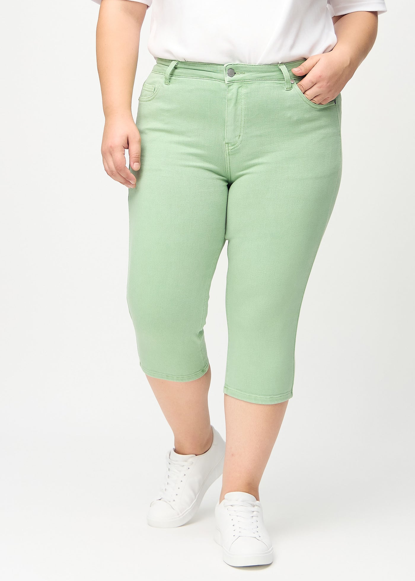 Lysegrønne skinny capris, modelnavn Mints, som sidder tæt til benet på en plus-size model, set forfra.