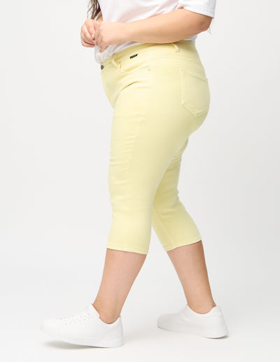 Lysegule skinny capris set fra siden på en plus-size model.