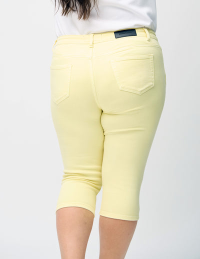 Lysegule skinny capris set bagfra tæt på en plus-size model for at vise detaljer.