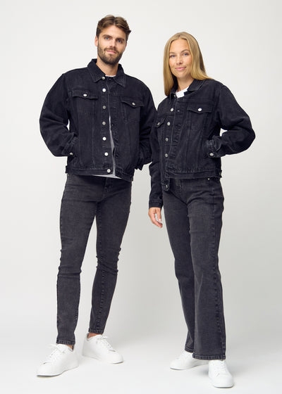 Fuldt billede af unisex mørkegrå denim jakke, set forfra på herre og dame model, med knapper og lommeplacering tydeligt synlige.